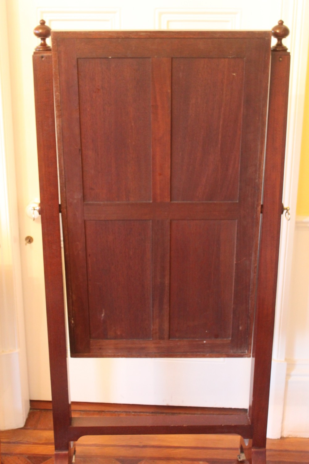 A full-length Sheraton style mahogany cheval dressing mirror with turned finials, splayed legs, brass castors, and a tilting frame. View X