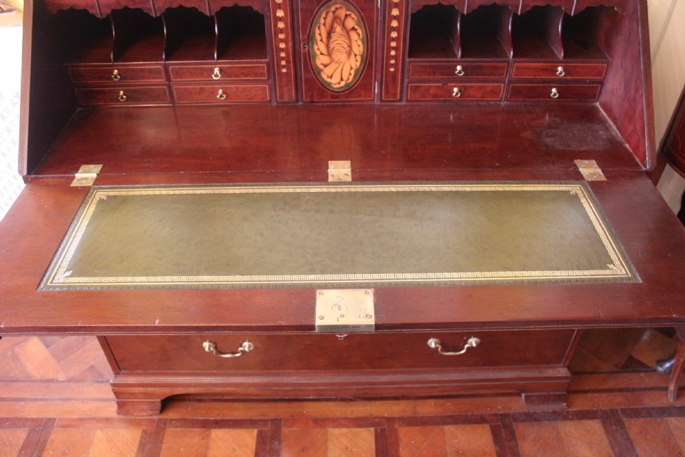 An 18th-century George III mahogany slant-front bureau featuring brass swan-neck handles and inlaid stringing over four graduated drawers. View X