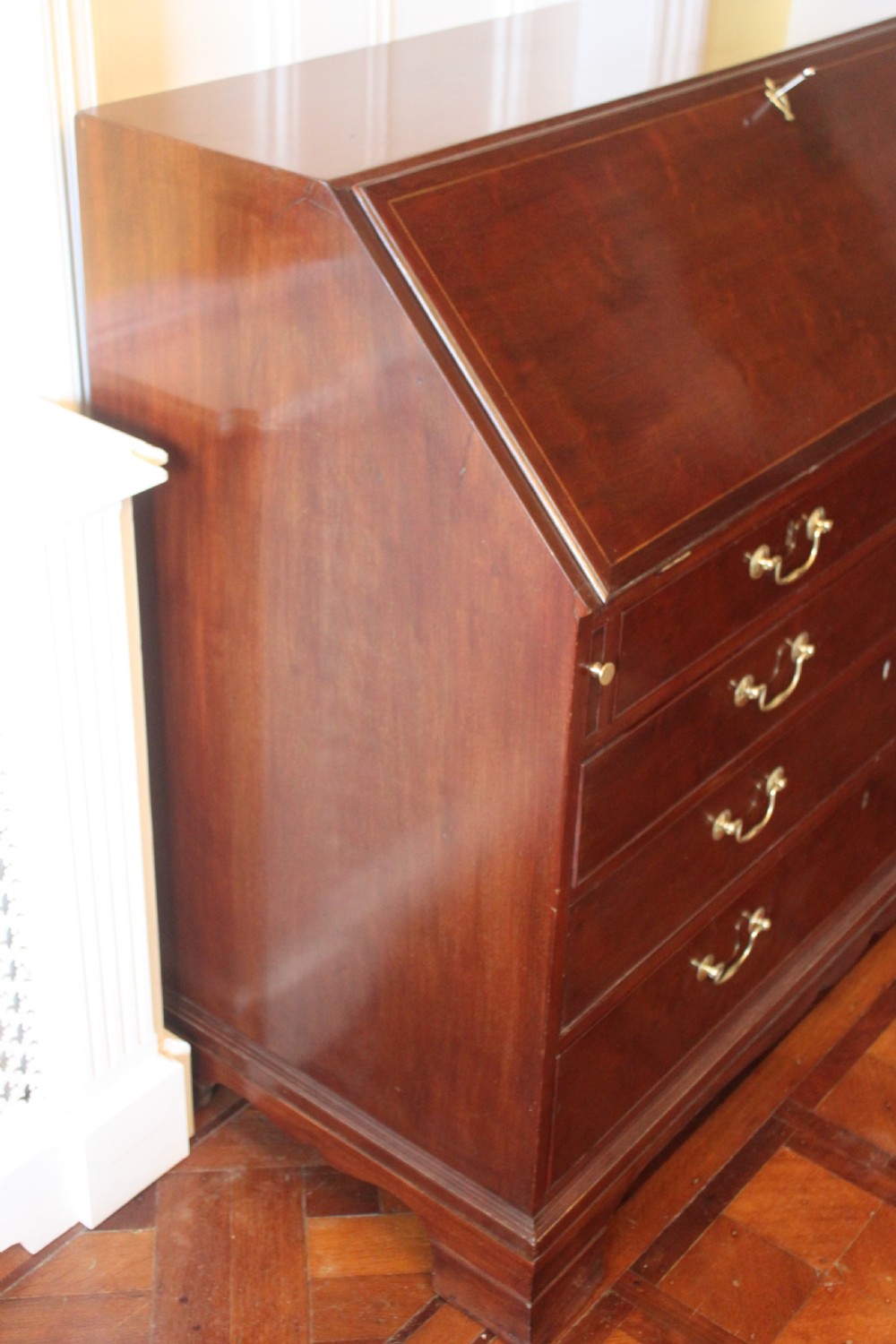 An 18th-century George III mahogany slant-front bureau featuring brass swan-neck handles and inlaid stringing over four graduated drawers. View XIV