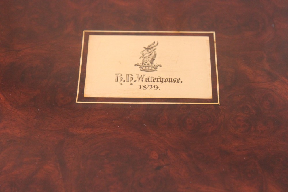 A rectangular Victorian burr walnut writing slope box featuring swirl veneer patterns, brass stringing inlay, a central engraved brass plaque, and a front keyhole escutcheon. View II