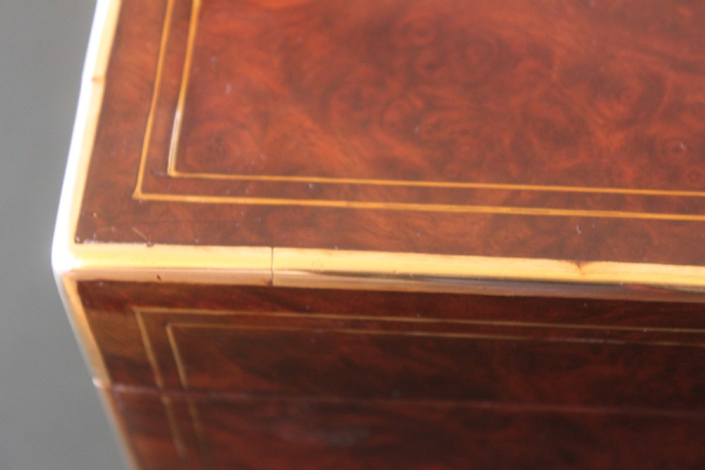 A rectangular Victorian burr walnut writing slope box featuring swirl veneer patterns, brass stringing inlay, a central engraved brass plaque, and a front keyhole escutcheon. View III