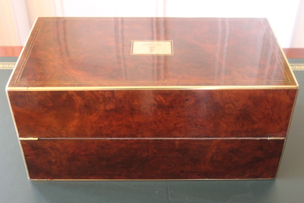 A rectangular Victorian burr walnut writing slope box featuring swirl veneer patterns, brass stringing inlay, a central engraved brass plaque, and a front keyhole escutcheon. View V