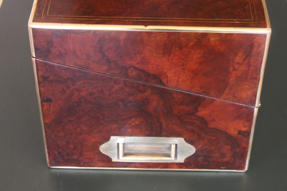 A rectangular Victorian burr walnut writing slope box featuring swirl veneer patterns, brass stringing inlay, a central engraved brass plaque, and a front keyhole escutcheon. View VI