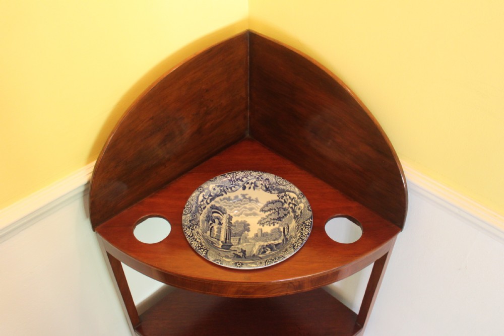 A Georgian mahogany corner washstand featuring an upper arched splashback, a central tier with a drawer, brass knobs, and curved splayed legs. View III