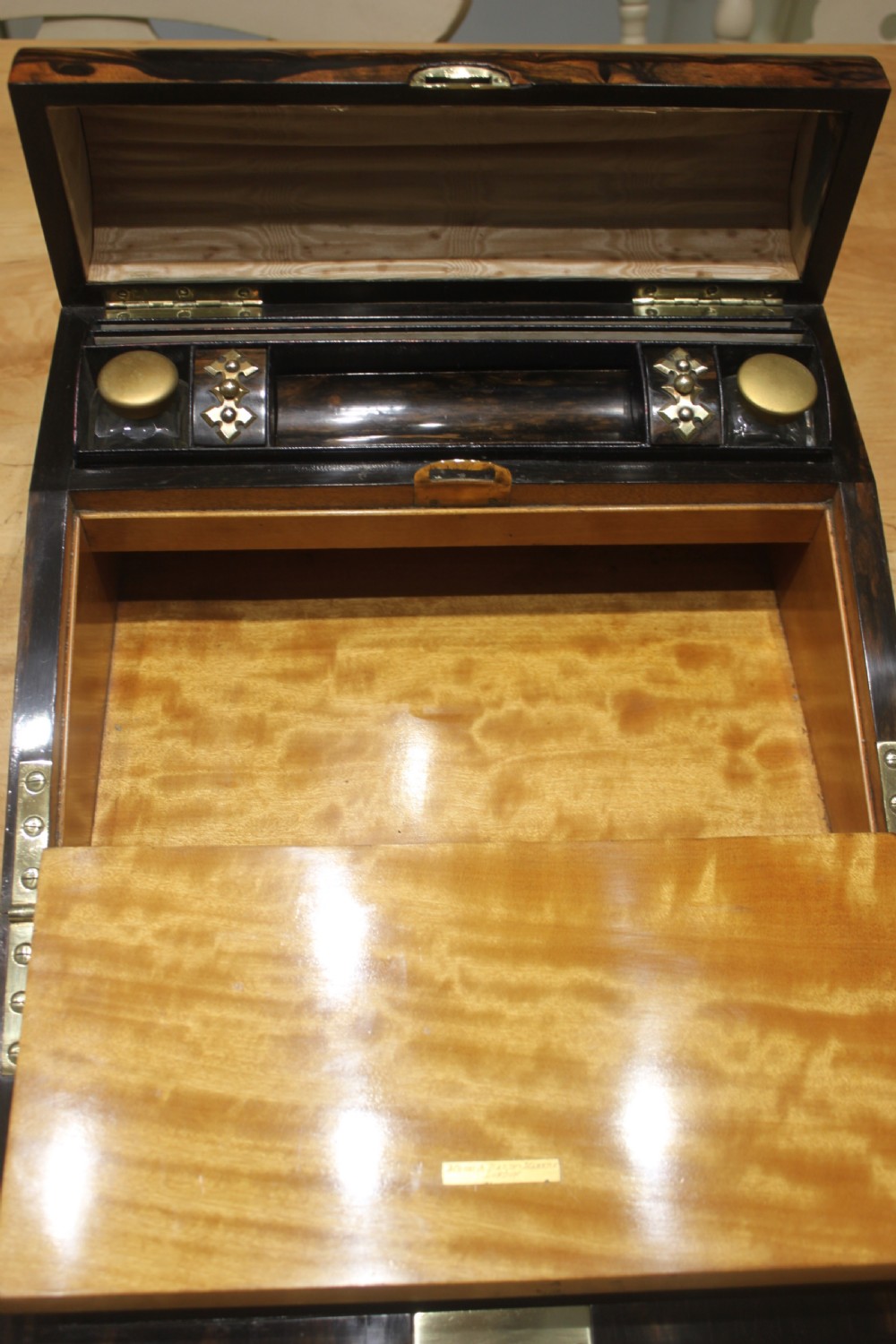 A Victorian coromandel wood writing slope featuring distinct dark and golden brown grain patterns, a rounded top section, and a central brass keyhole. View X
