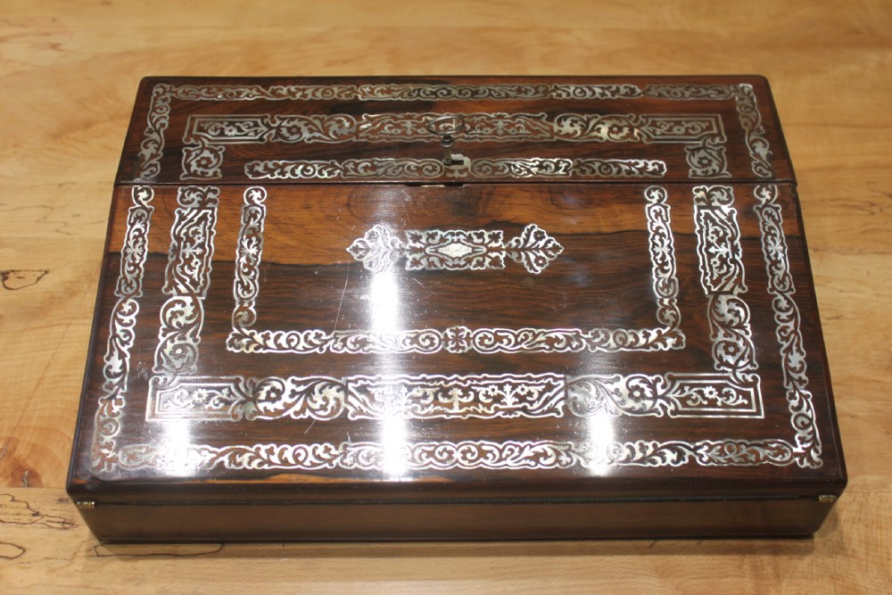 A dark rosewood rectangular writing slope box decorated with intricate mother-of-pearl foliate floral inlay and a central keyhole escutcheon.