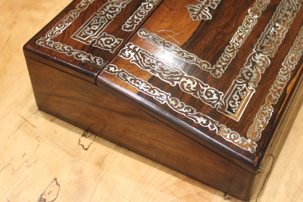A dark rosewood rectangular writing slope box decorated with intricate mother-of-pearl foliate floral inlay and a central keyhole escutcheon. View II