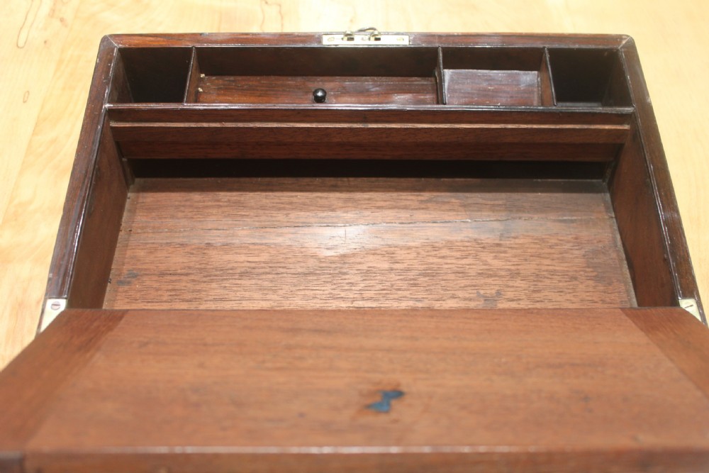 A rectangular Victorian rosewood writing box featuring flush brass corner brackets, a central engraved brass cartouche, and a key inserted into the front keyhole. View X