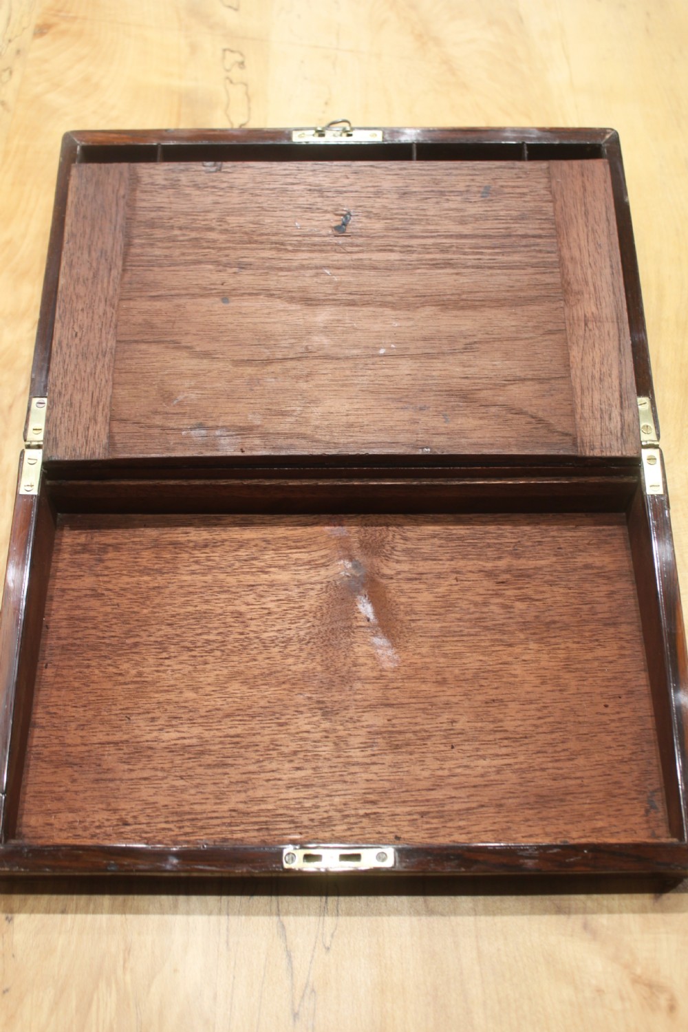 A rectangular Victorian rosewood writing box featuring flush brass corner brackets, a central engraved brass cartouche, and a key inserted into the front keyhole. View XII