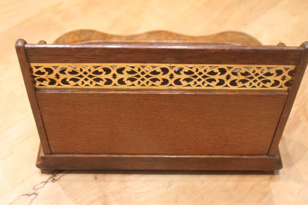 Late Victorian oak standish featuring a stationary gallery with pierced brass trim, two square glass inkwells with brass lids, and a carved pen groove. View VI