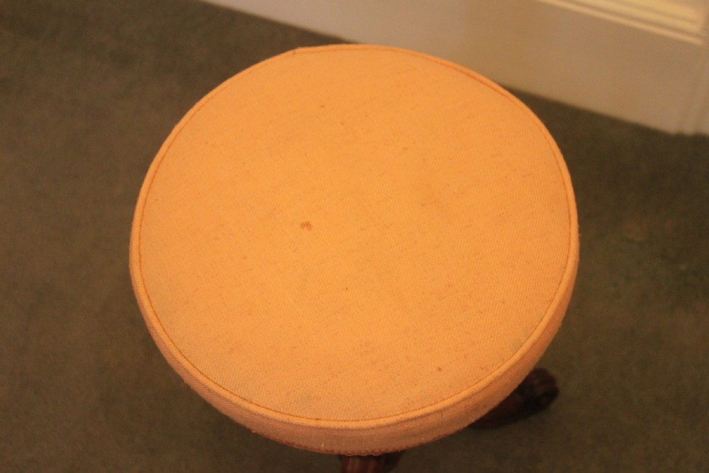 A Victorian mahogany revolving piano stool featuring a circular beige upholstered seat, a turned pedestal with acanthus leaf carving, and tripod scroll feet. View VIII