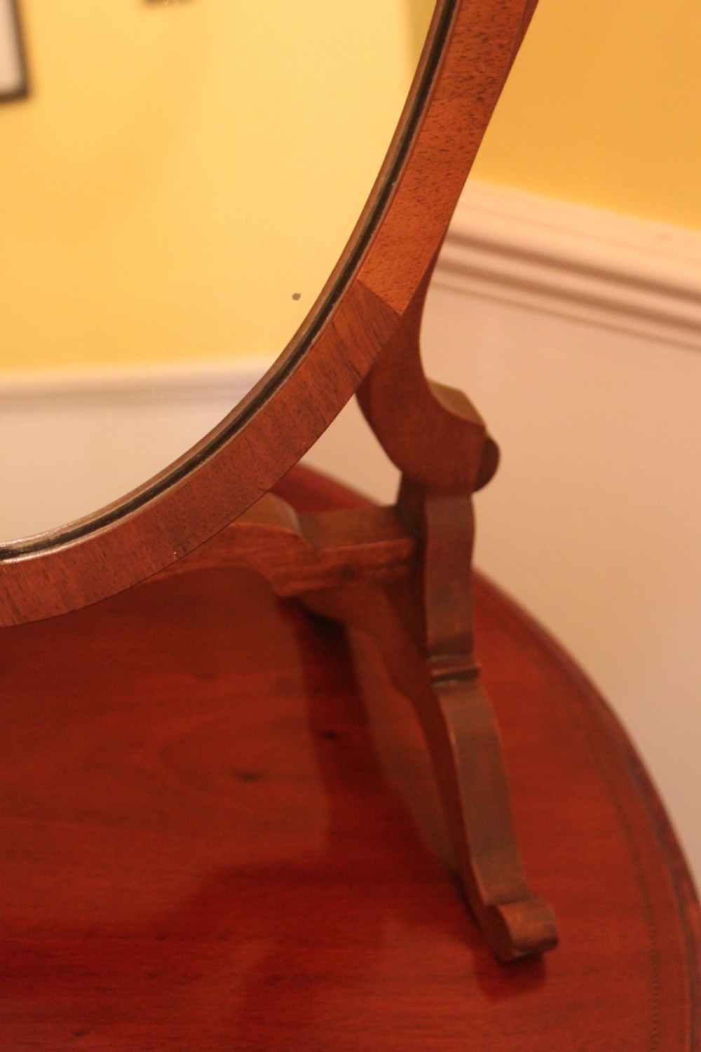 An Edwardian Hepplewhite style mahogany toilet mirror featuring a shield-shaped frame supported by two curved upright legs. View V