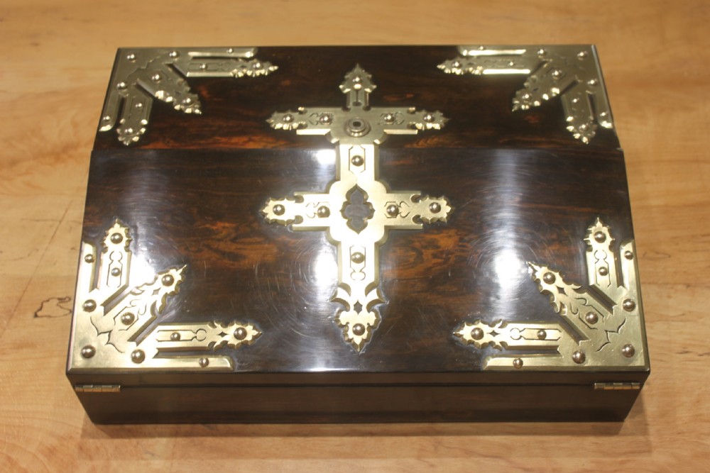 A rectangular dark coromandel wood writing slope box decorated with ornate Gothic Revival brass corner mounts and central brass straps.