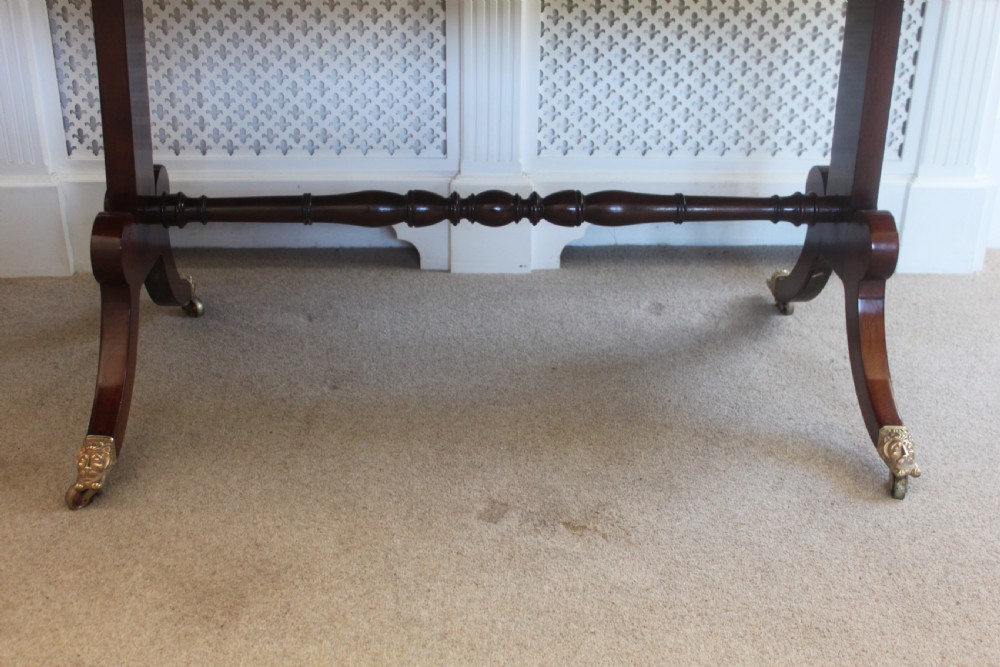 An early nineteenth-century mahogany sofa table featuring two drop leaves, two frieze drawers with knob handles, a turned central stretcher, and splayed legs with brass paw feet and castors. View V