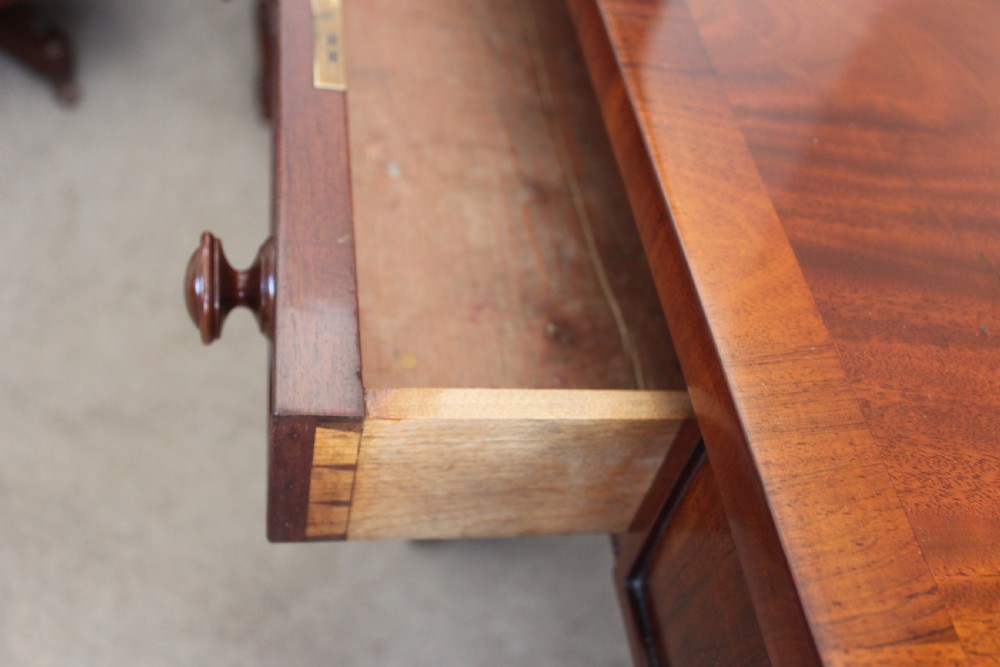 An early nineteenth-century mahogany sofa table featuring two drop leaves, two frieze drawers with knob handles, a turned central stretcher, and splayed legs with brass paw feet and castors. View IX