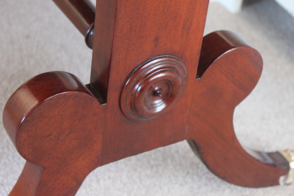 An early nineteenth-century mahogany sofa table featuring two drop leaves, two frieze drawers with knob handles, a turned central stretcher, and splayed legs with brass paw feet and castors. View XI