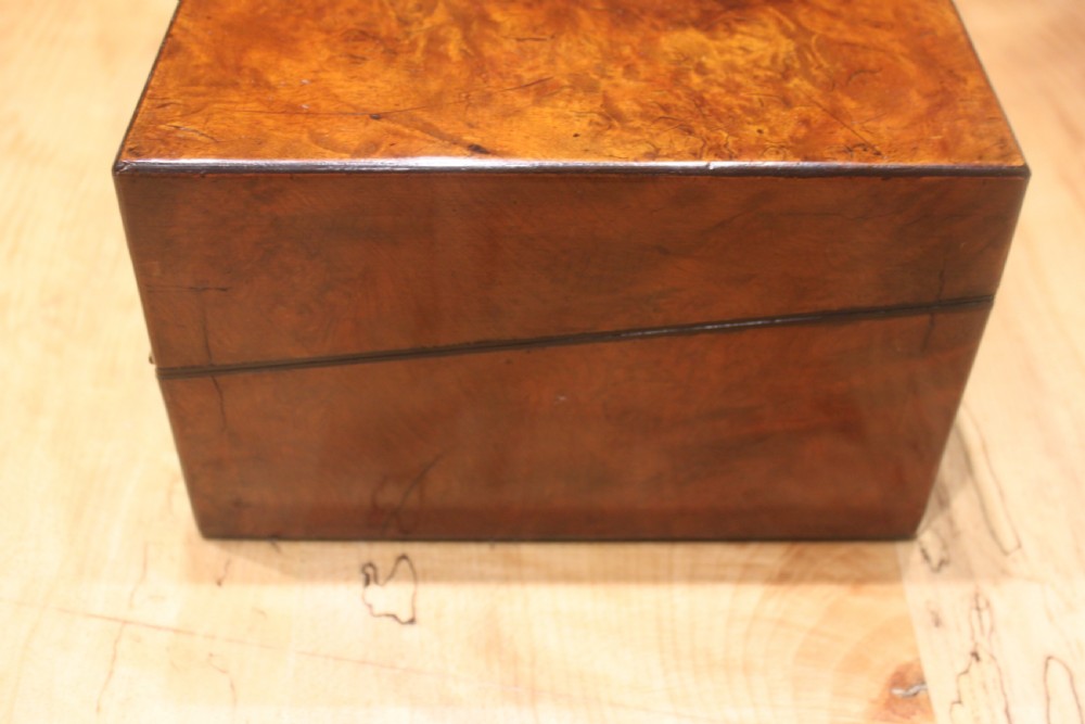 A rectangular Victorian burr walnut writing slope featuring a brass cartouche on top and a brass escutcheon with key on the front. View III