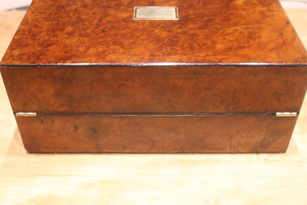A rectangular Victorian burr walnut writing slope featuring a brass cartouche on top and a brass escutcheon with key on the front. View V