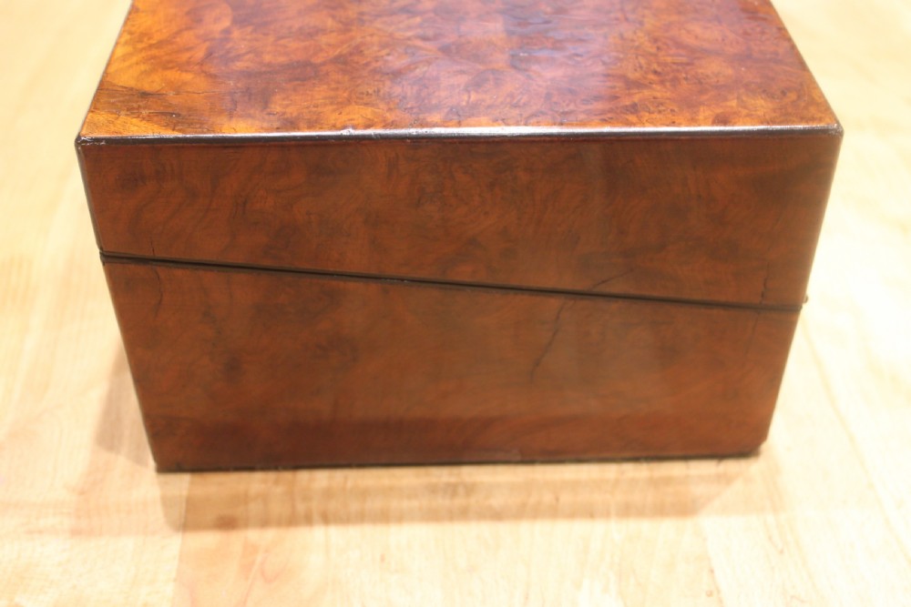 A rectangular Victorian burr walnut writing slope featuring a brass cartouche on top and a brass escutcheon with key on the front. View VI