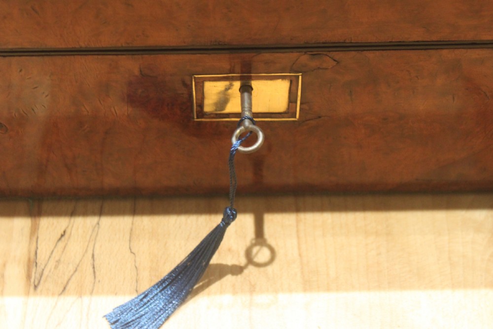 A rectangular Victorian burr walnut writing slope featuring a brass cartouche on top and a brass escutcheon with key on the front. View XV