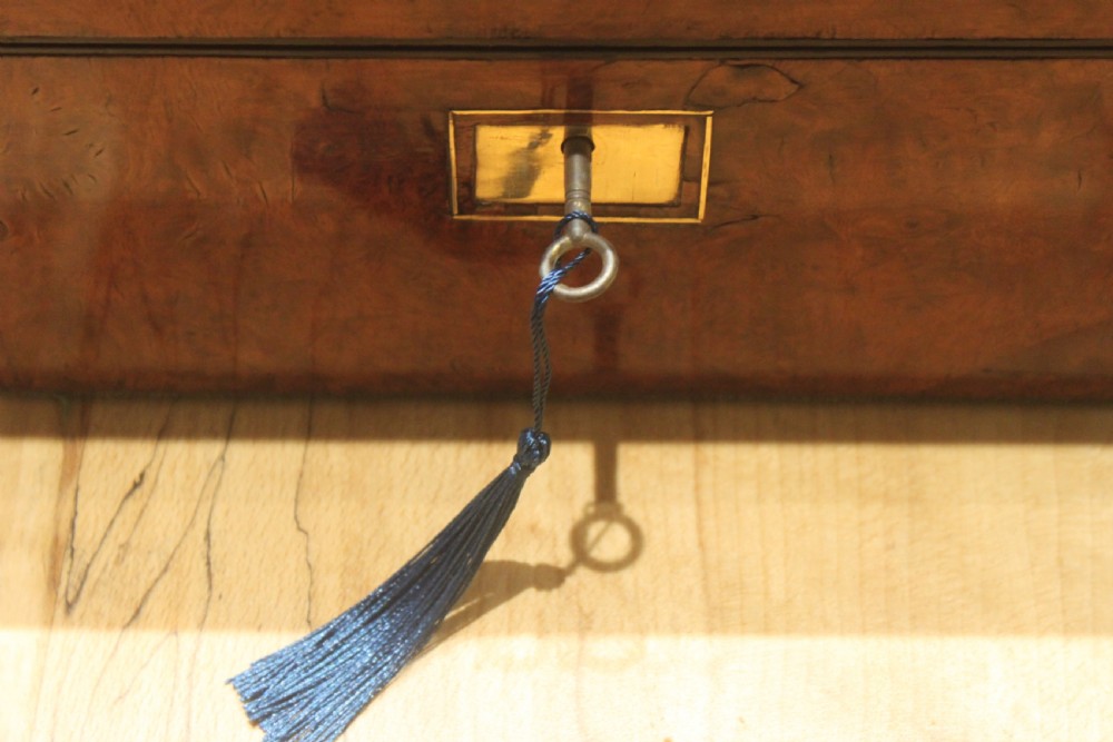 A rectangular Victorian burr walnut writing slope featuring a brass cartouche on top and a brass escutcheon with key on the front. View XVI