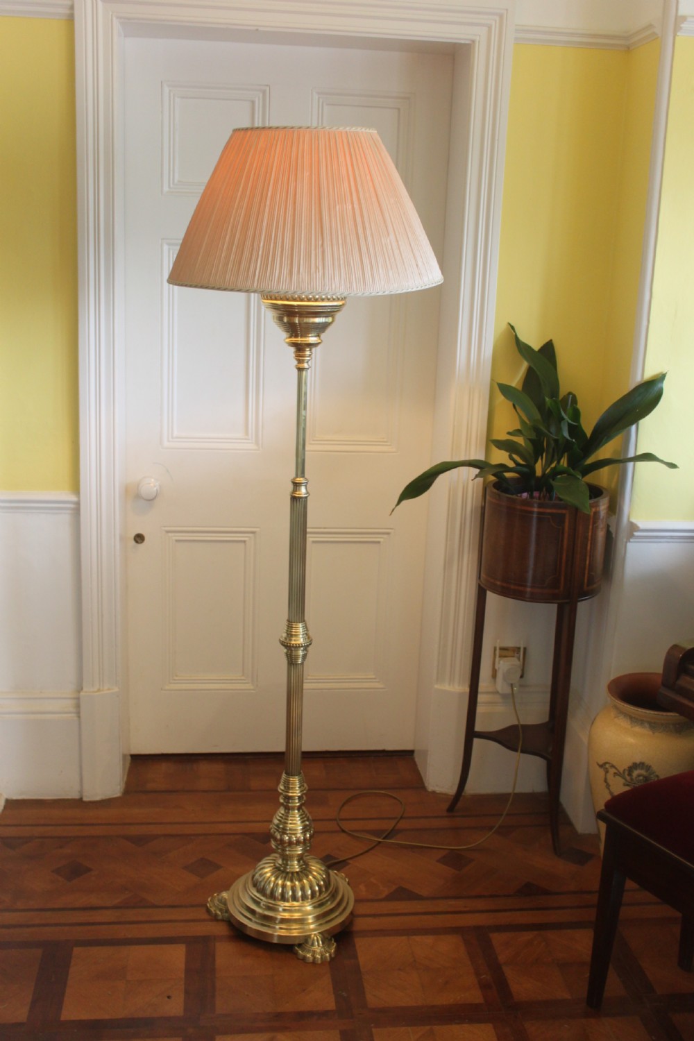 A tall Victorian brass telescopic standard lamp featuring a reeded column, gadrooned base, and a pleated fabric lampshade.