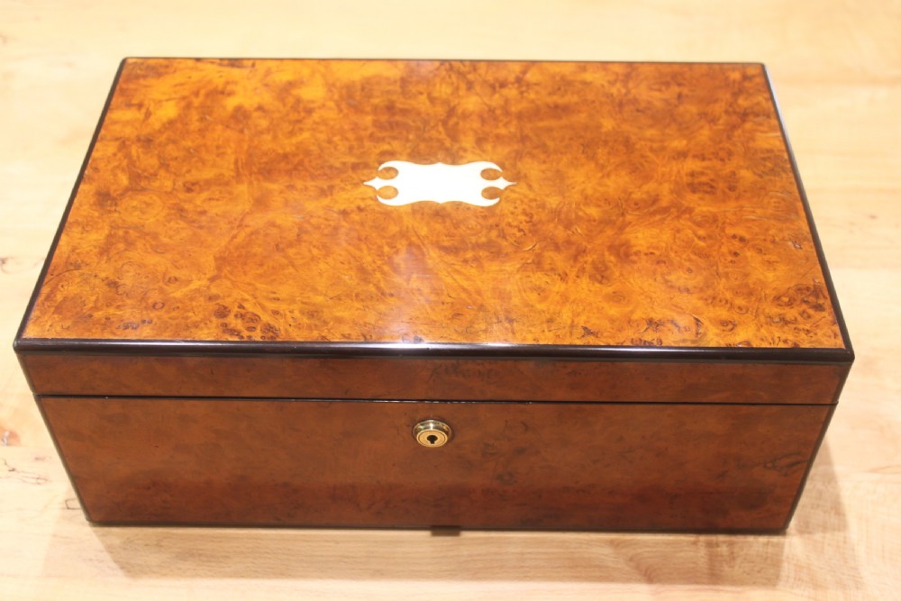 A rectangular antique burr walnut writing slope with an inlaid central cartouche and a brass circular Bramah lock on the front face.
