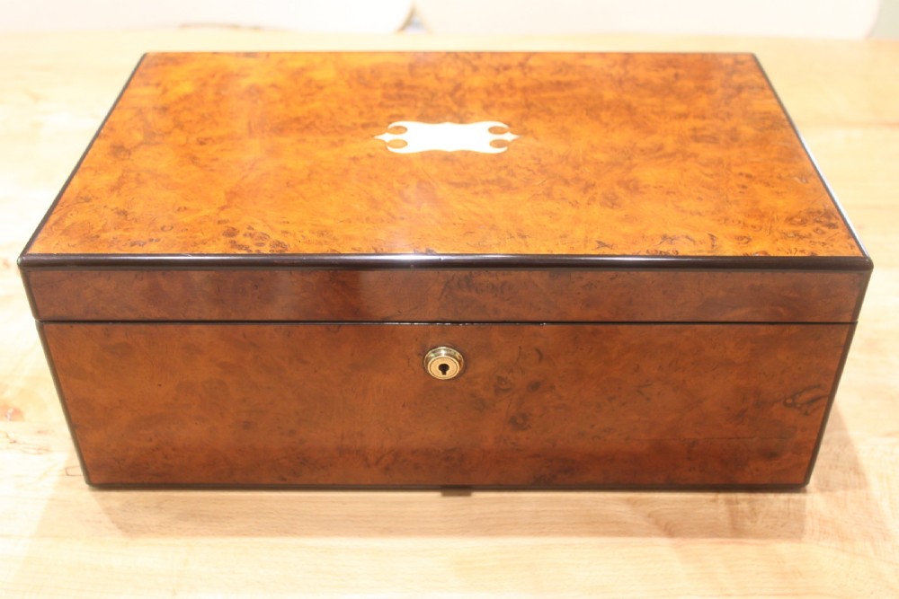 A rectangular antique burr walnut writing slope with an inlaid central cartouche and a brass circular Bramah lock on the front face. View II
