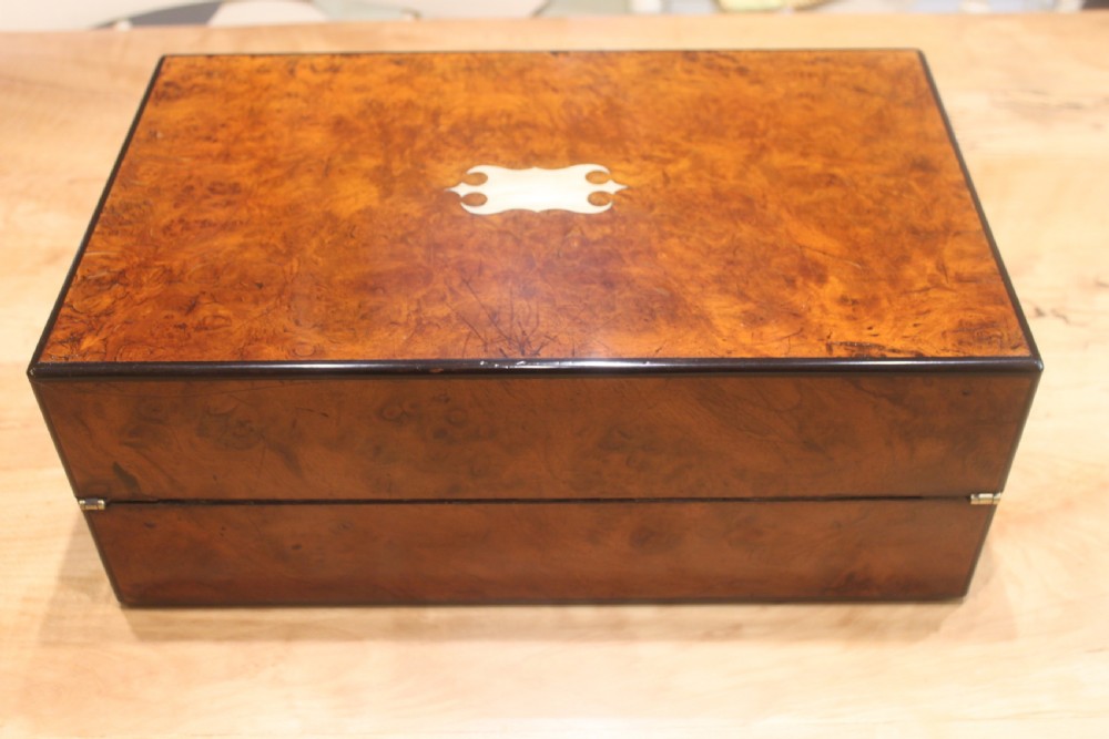 A rectangular antique burr walnut writing slope with an inlaid central cartouche and a brass circular Bramah lock on the front face. View V