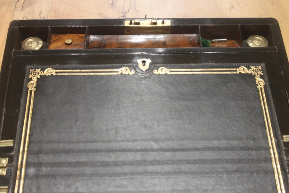 A rectangular Victorian walnut writing slope featuring brass bound corners, a central rectangular brass cartouche, and a key inserted into the front keyhole plate. View VI
