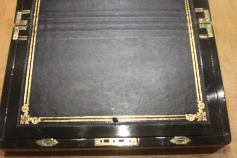 A rectangular Victorian walnut writing slope featuring brass bound corners, a central rectangular brass cartouche, and a key inserted into the front keyhole plate. View VII