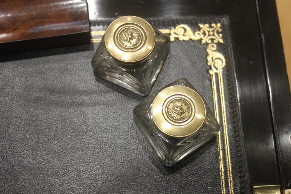 A rectangular Victorian walnut writing slope featuring brass bound corners, a central rectangular brass cartouche, and a key inserted into the front keyhole plate. View X