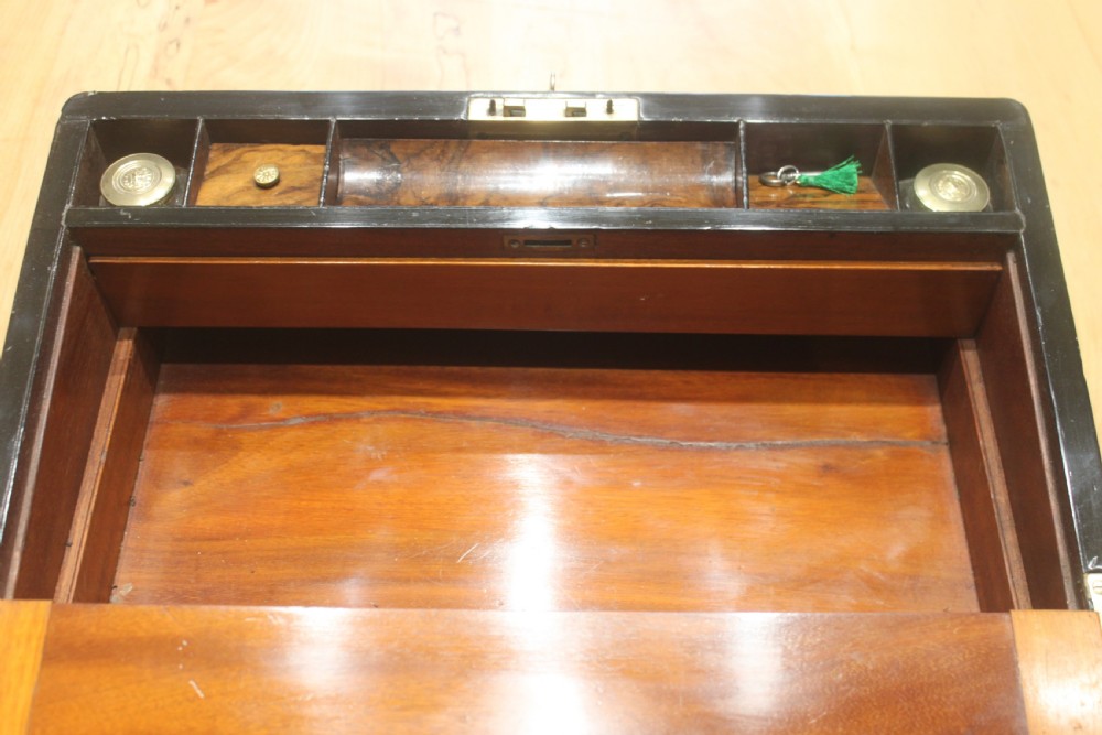 A rectangular Victorian walnut writing slope featuring brass bound corners, a central rectangular brass cartouche, and a key inserted into the front keyhole plate. View XI