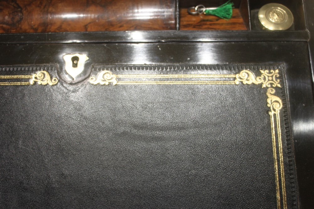 A rectangular Victorian walnut writing slope featuring brass bound corners, a central rectangular brass cartouche, and a key inserted into the front keyhole plate. View XIII