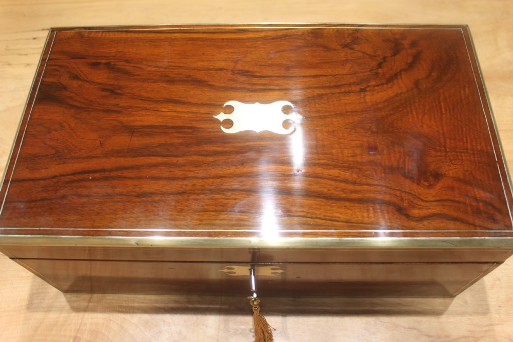 A rectangular dark walnut box featuring brass corner edging, an inlaid brass cartouche on the lid, and a brass escutcheon with a key and tassel. View V