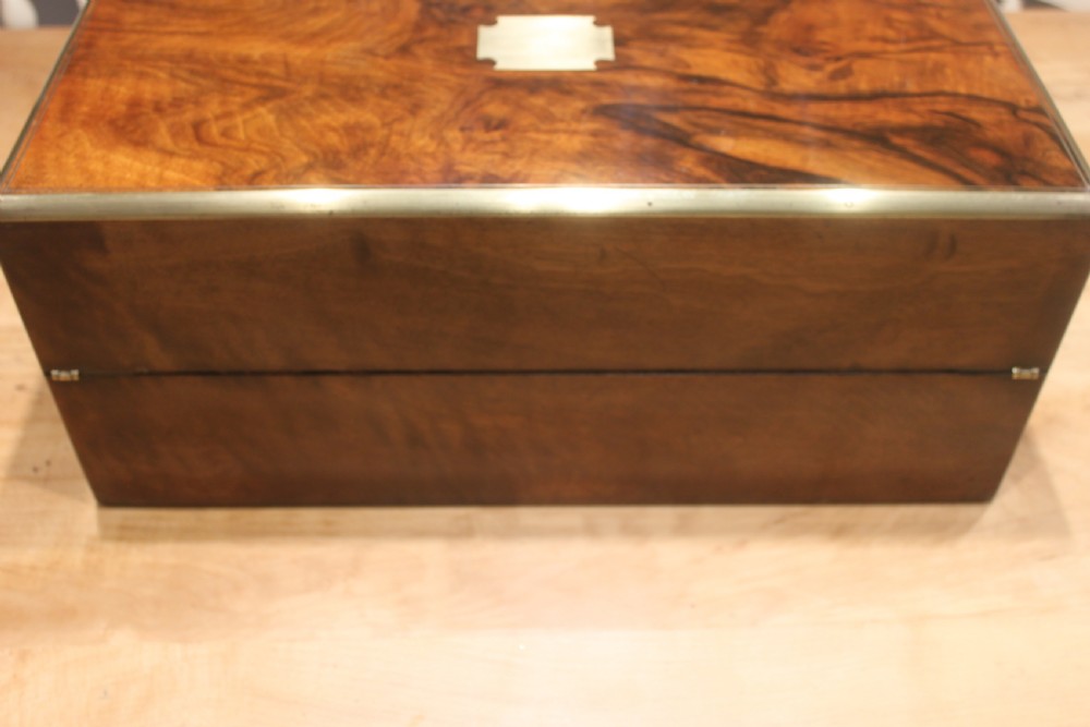 A rectangular Victorian writing slope crafted from figured walnut with brass binding, a top brass cartouche, and a brass key escutcheon with a tassel. View IV