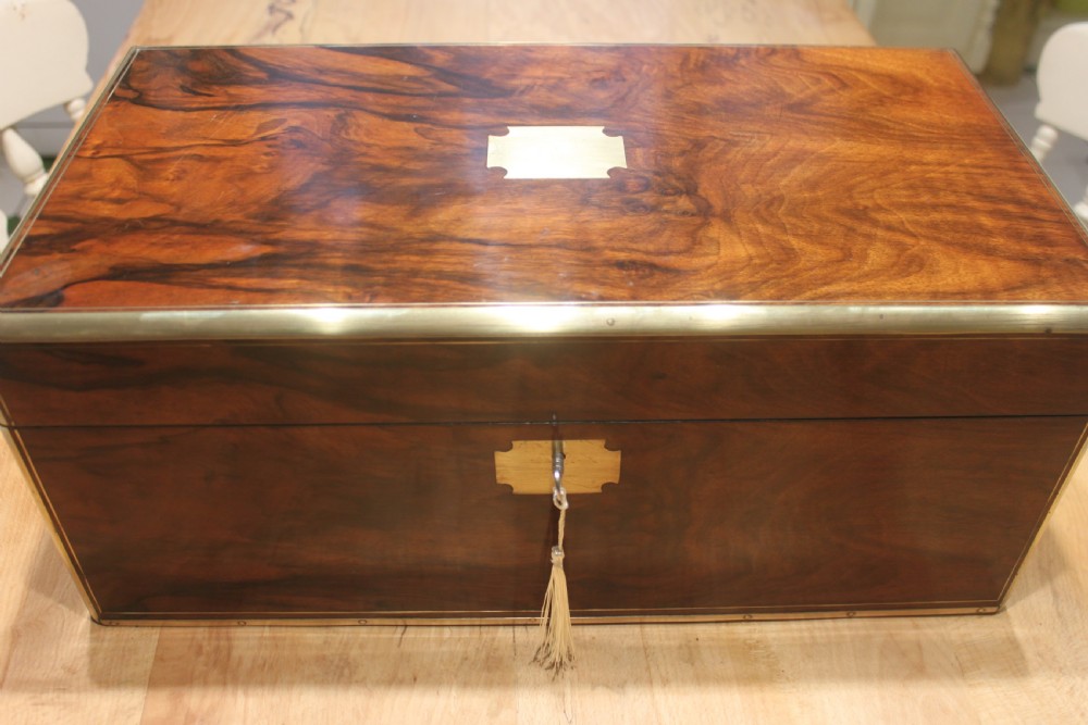 A rectangular Victorian writing slope crafted from figured walnut with brass binding, a top brass cartouche, and a brass key escutcheon with a tassel. View VI
