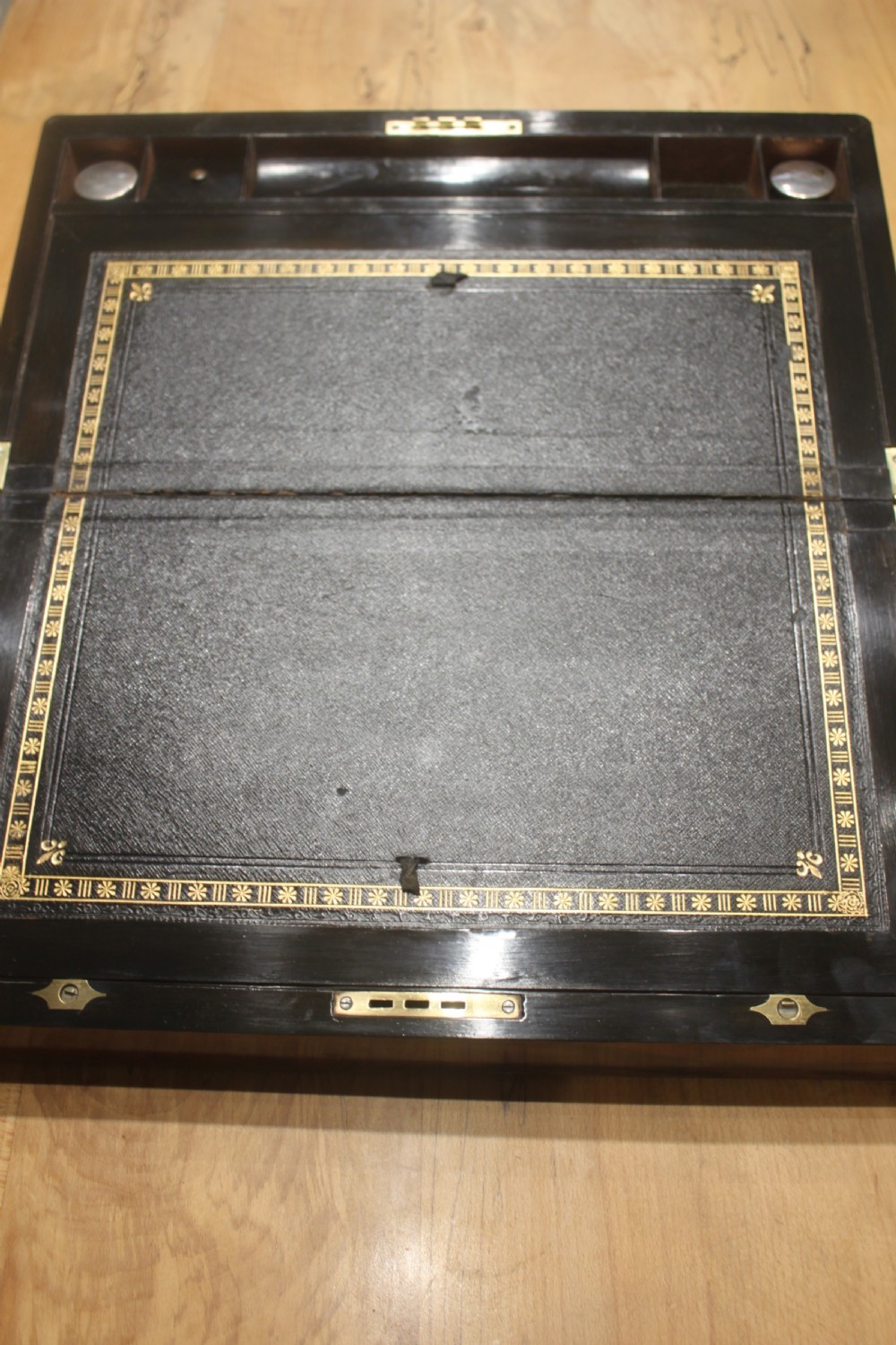 A rectangular Victorian writing slope crafted from figured walnut with brass binding, a top brass cartouche, and a brass key escutcheon with a tassel. View VII