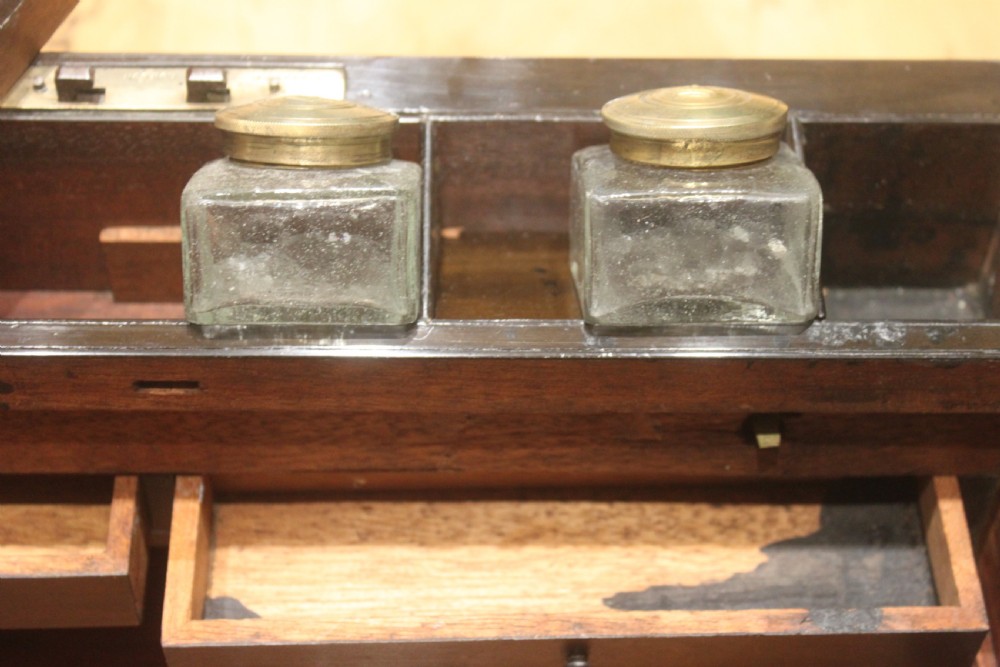 A closed Victorian writing slope crafted from figured walnut veneer featuring brass edging, line inlay, a brass cartouche, and a key inserted in the Bramah lock with a tassel. View XVIII