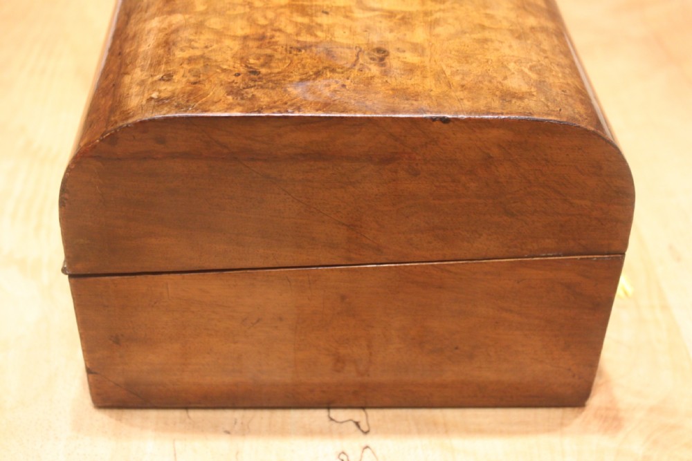 A rectangular Victorian burr walnut writing slope box featuring a domed lid, central inlaid cartouche, and a key inserted into the brass escutcheon. View VI