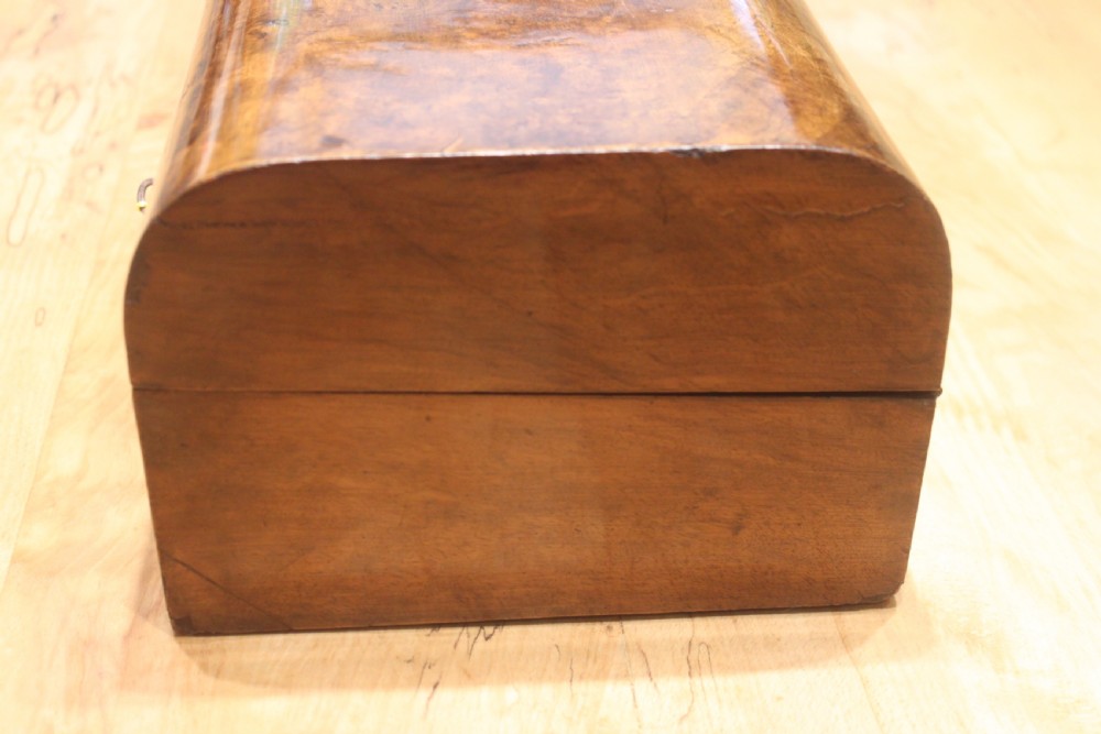 A rectangular Victorian burr walnut writing slope box featuring a domed lid, central inlaid cartouche, and a key inserted into the brass escutcheon. View VIII