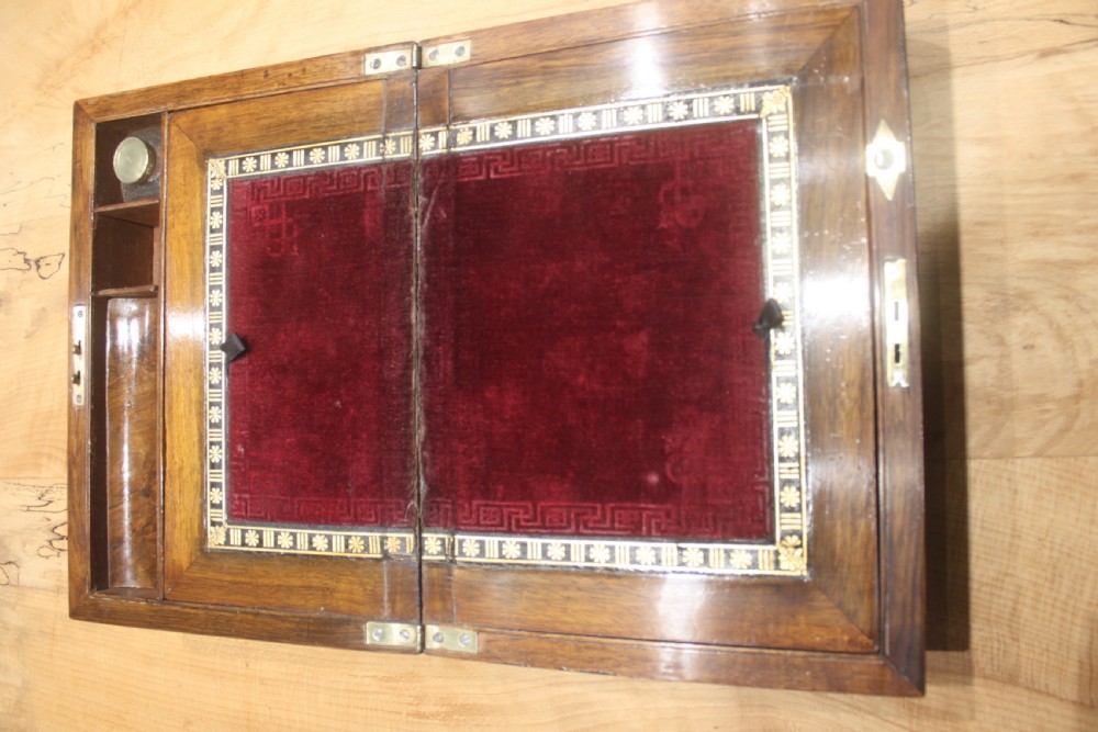 A rectangular Victorian burr walnut writing slope box featuring a domed lid, central inlaid cartouche, and a key inserted into the brass escutcheon. View IX