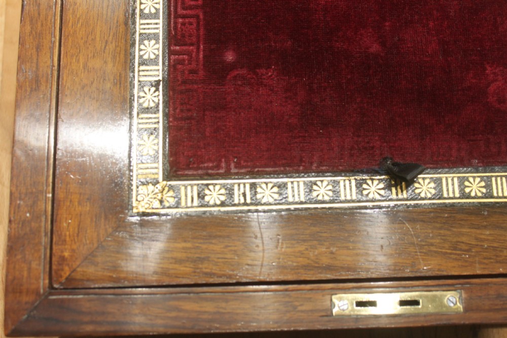 A rectangular Victorian burr walnut writing slope box featuring a domed lid, central inlaid cartouche, and a key inserted into the brass escutcheon. View XI