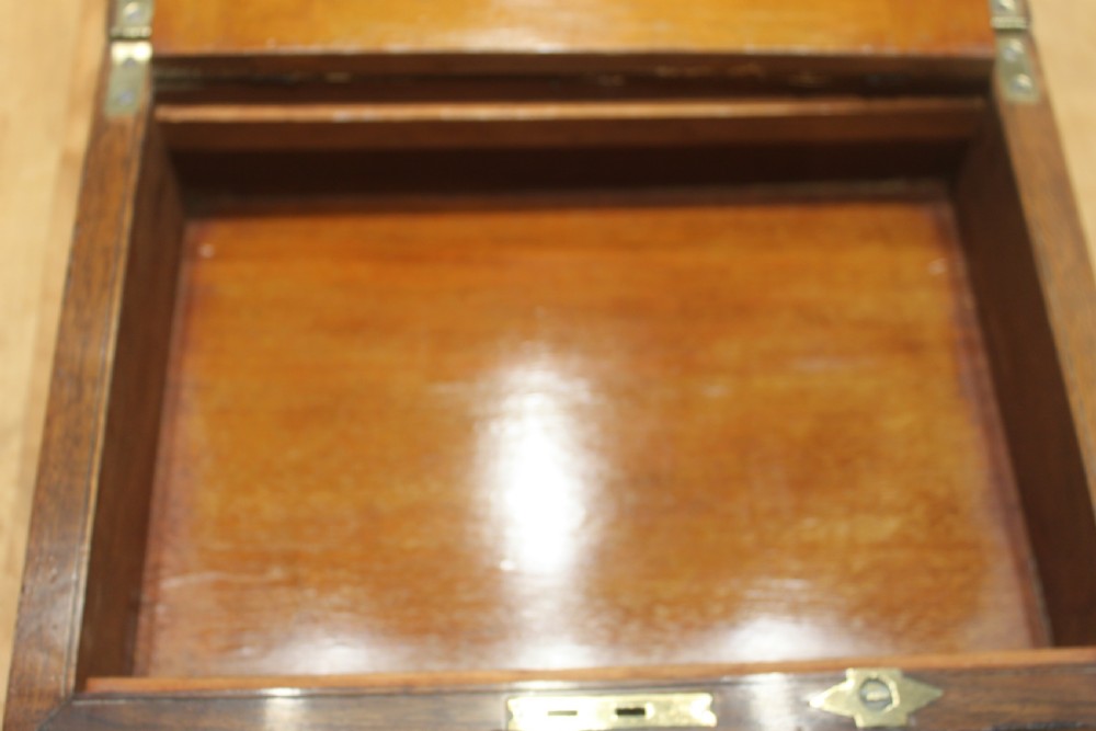 A rectangular Victorian burr walnut writing slope box featuring a domed lid, central inlaid cartouche, and a key inserted into the brass escutcheon. View XII