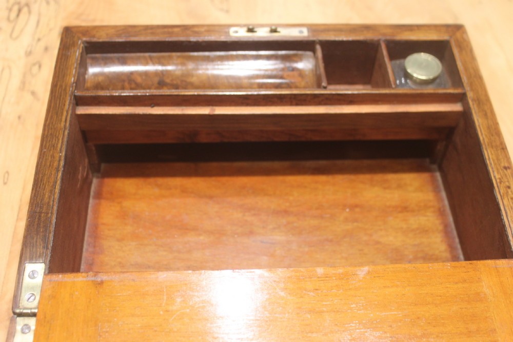 A rectangular Victorian burr walnut writing slope box featuring a domed lid, central inlaid cartouche, and a key inserted into the brass escutcheon. View XIII