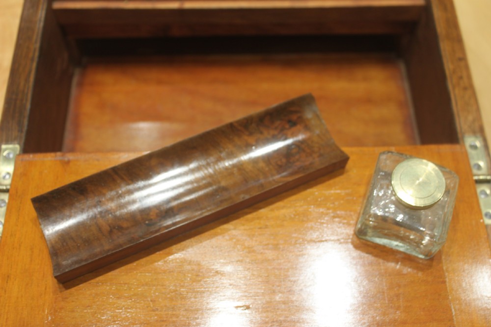 A rectangular Victorian burr walnut writing slope box featuring a domed lid, central inlaid cartouche, and a key inserted into the brass escutcheon. View XIV