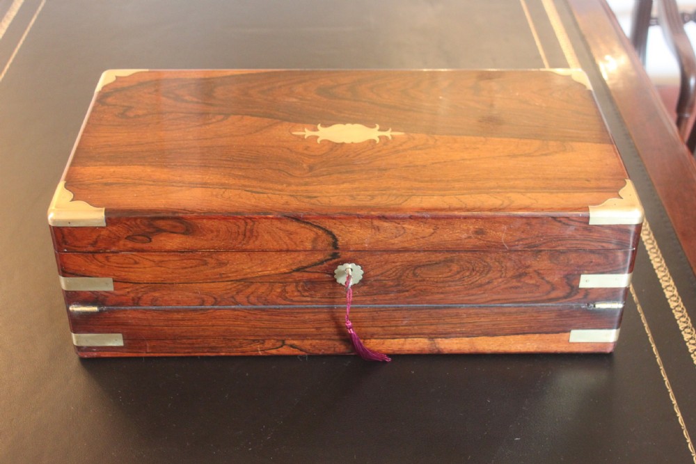 A rectangular dark rosewood writing slope box with brass corner mounts, brass cartouche inlay, and a central brass keyhole with a tassel. View II