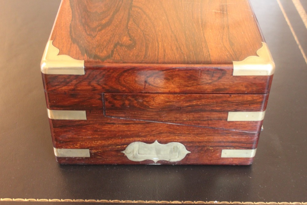 A rectangular dark rosewood writing slope box with brass corner mounts, brass cartouche inlay, and a central brass keyhole with a tassel. View III