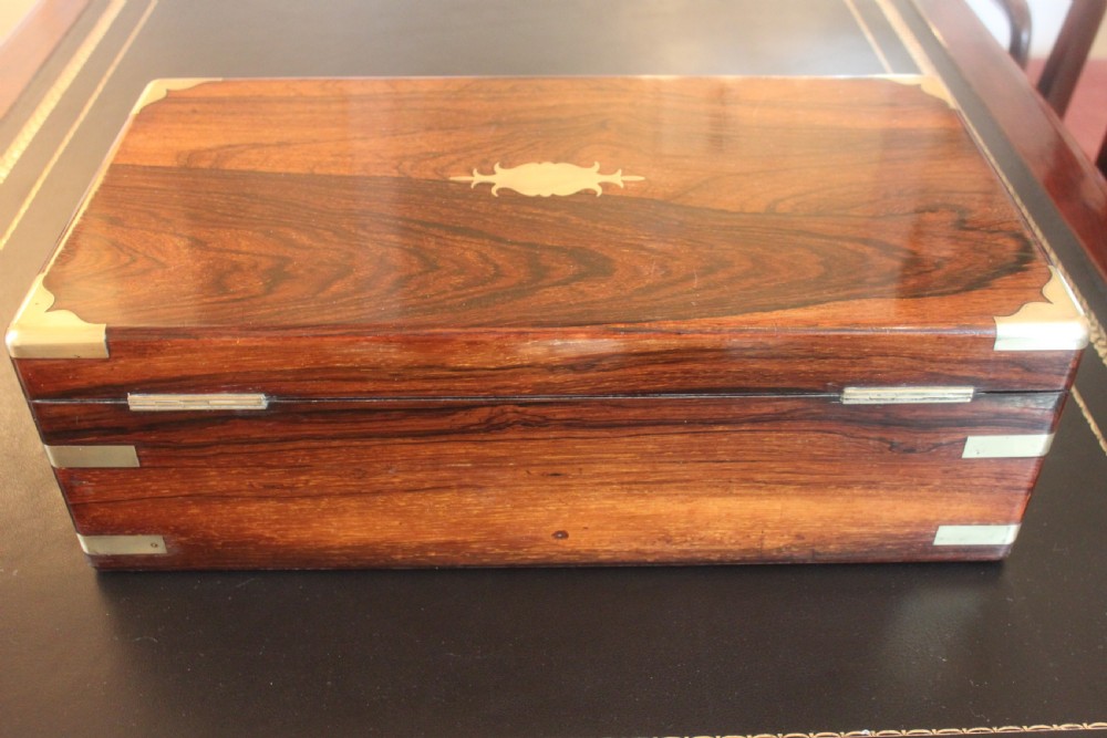 A rectangular dark rosewood writing slope box with brass corner mounts, brass cartouche inlay, and a central brass keyhole with a tassel. View IV