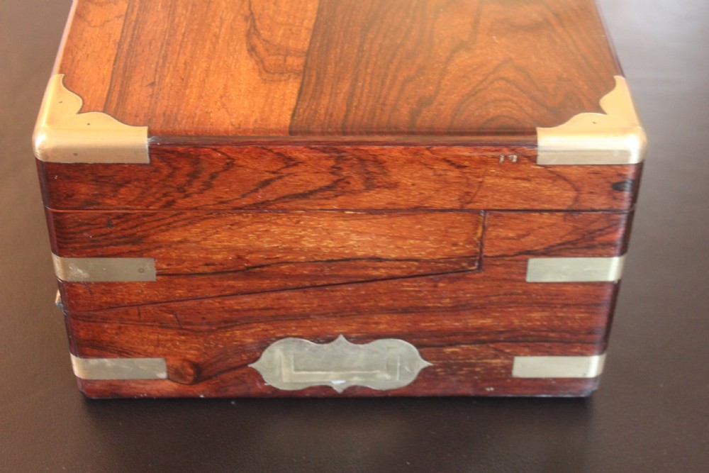 A rectangular dark rosewood writing slope box with brass corner mounts, brass cartouche inlay, and a central brass keyhole with a tassel. View V